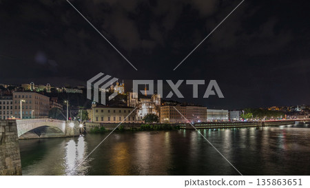 Panorama showing night timelapse of Lyon's cityscape with the red suspension footbridge over the Saone River. France Panorama showing night timelapse of Lyon's cityscape with the red suspension footbridge over the Saone River. France 135863651