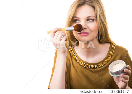 Smiling woman applying face powder 135863927