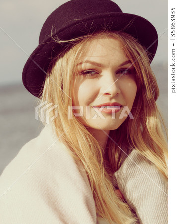 Woman wearing hat, sea in background Woman wearing hat, sea in background 135863935