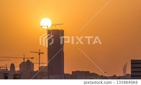 A tower in Doha timelapse, Qatar, under construction, silhouetted against the sunset. 135864068