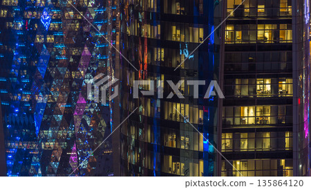 Windows timelapse of the multi-storey building of glass and steel office lighting and working people within 135864120