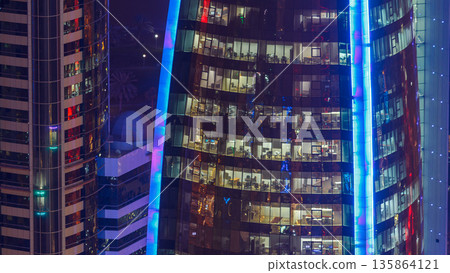 Windows timelapse of the multi-storey building of glass and steel office lighting and working people within 135864121