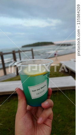特寫鏡頭,展現一杯清爽的藍色飲品,背景是蔚藍的大海。 特寫鏡頭,展現一杯清爽的藍色飲品,背景是蔚藍的大海。 135864209