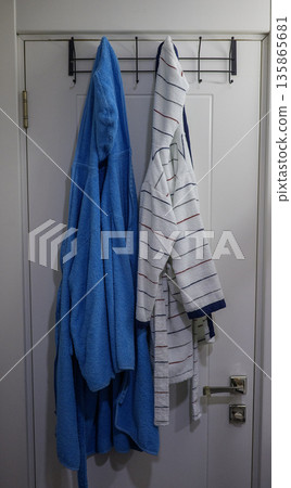 Terry bathrobes hang on hooks in the bathroom Terry bathrobes hang on hooks in the bathroom 135865681
