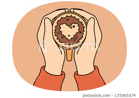 Coffee with foam heart in hands of person drinking hot drink from cup and enjoying aroma 135865874
