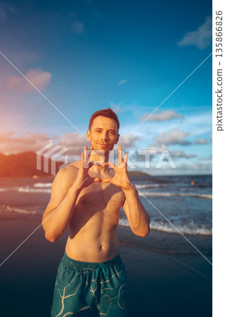 handsome white man with athletic muscular body standing at beach at sunny sunset, attractive male athlete walking at sea or ocean shore handsome white man with athletic muscular body standing at beach at sunny sunset, attractive male athlete walking at sea or ocean shore 135866826