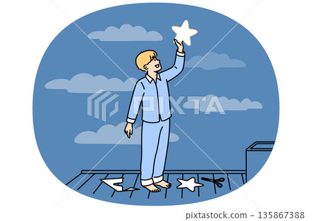Little boy puts paper star to sky, thinking about endless space and galaxies, dressed in pajamas 135867388