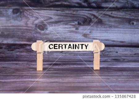 Certainty symbol. A wooden stick secured by Clothespins set over beautiful Realistic Wooden Texture Background. Business and Certainty concept with copy space 135867428