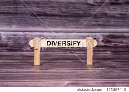 Diversify symbol. Wooden stick held by Clothespins, beautiful Realistic Grunge Wooden Background. Business and Diversify concept with copy space Diversify symbol. Wooden stick held by Clothespins, beautiful Realistic Grunge Wooden Background. Business and Diversify concept with copy space 135867440