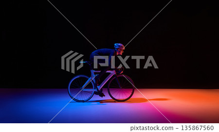 Professional cyclist riding road bike under neon lighting with copy space 135867560