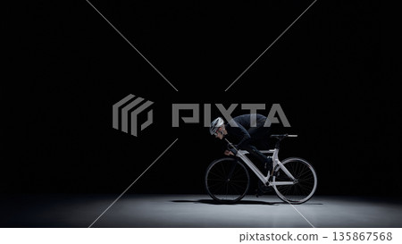 Cyclist riding road bike under dramatic studio lighting. Cyclist riding road bike under dramatic studio lighting. 135867568