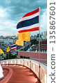 Thai flag waving over Bangkok city skyline with temples, Thailand national flag against urban panorama grand palace view  135867601
