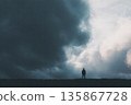 Solitary Figure Stands On a Hill Under Dramatic Stormy Sky With Rays of Light 135867728