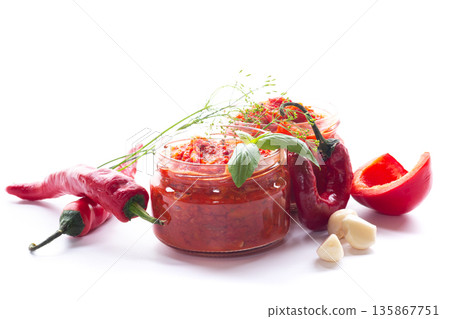 Tasty red chili spread in jars surrounded by peppers Tasty red chili spread in jars surrounded by peppers 135867751