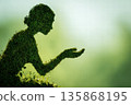 Green Hedge Silhouette Kneeling With Open Hand In Sunlit Outdoor Setting 135868195