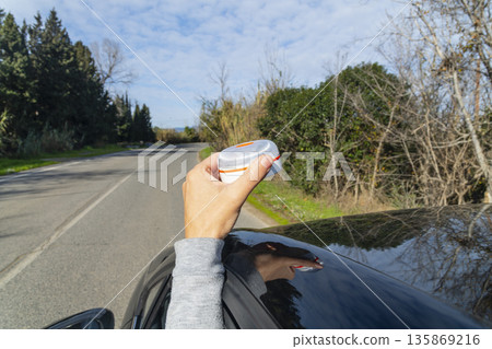 a man placing a V16 warning beacon on the car 135869216