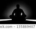 Silhouette of a Person in Meditation Pose With Backlit Background and Calm Focus 135869407