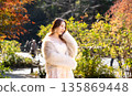 Smiling young woman in autumn park with autumn leaves in the background 135869448