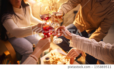 Friends clinking wine glasses during home wine tasting evening. Friends clinking wine glasses during home wine tasting evening. 135869511