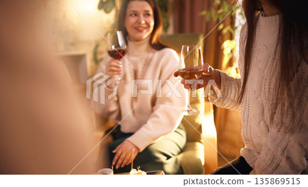 Friends enjoying wine tasting together in cozy living room. Friends enjoying wine tasting together in cozy living room. 135869515