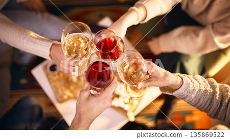 Friends clinking wine glasses during cozy evening gathering at home. Friends clinking wine glasses during cozy evening gathering at home. 135869522