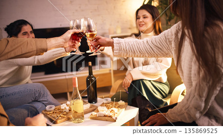 Friends clinking wine glasses at cozy home gathering. 135869525