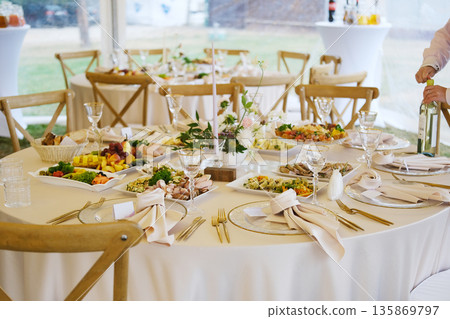 Elegant wedding menu displayed on a beautifully set table with gourmet dishes, fine glassware, and floral decorations, creating a romantic dining atmosphere for guests Elegant wedding menu displayed on a beautifully set table with gourmet dishes, fine glassware, and floral decorations, creating a romantic dining atmosphere for guests 135869797
