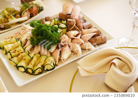 Elegant wedding menu featuring beautifully arranged appetizers on a white plate, garnished with fresh herbs, creating a delightful culinary experience for guests at a celebration 135869810