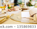Elegant table setting featuring blank place cards on fine china plates, surrounded by luxurious cutlery and soft floral arrangements, ideal for event design mock up with copy space 135869833