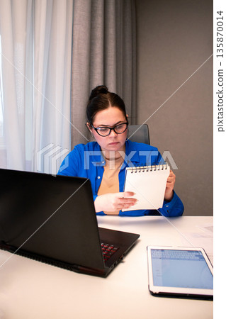 Working remotely from cozy home interior. Woman enjoys location-independent work with laptop in comfortable home settings. Freedom and flexibility of working from anywhere. Modern technology concept Working remotely from cozy home interior. Woman enjoys location-independent work with laptop in comfortable home settings. Freedom and flexibility of working from anywhere. Modern technology concept 135870014