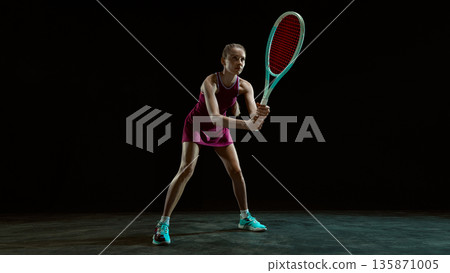 Focused female tennis player ready to receive ball in studio. Focused female tennis player ready to receive ball in studio. 135871005