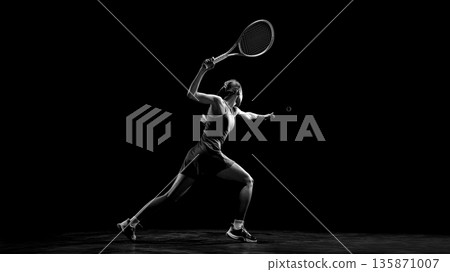 Female tennis player performing powerful forehand stroke in dark studio. Female tennis player performing powerful forehand stroke in dark studio. 135871007