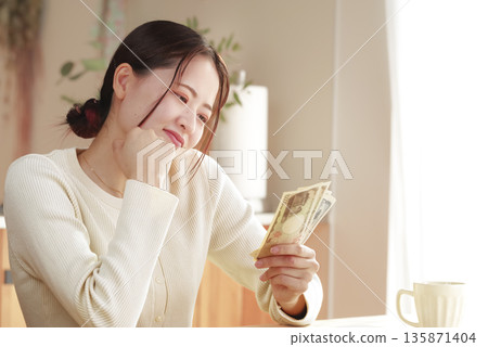 A young woman staring at her money and thinking about how to spend it A young woman staring at her money and thinking about how to spend it 135871404