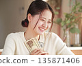 A woman who looks happy with money in her hands 135871406