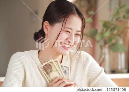 A woman who looks happy with money in her hands 135871406