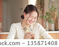 A woman who looks happy with money in her hands 135871408