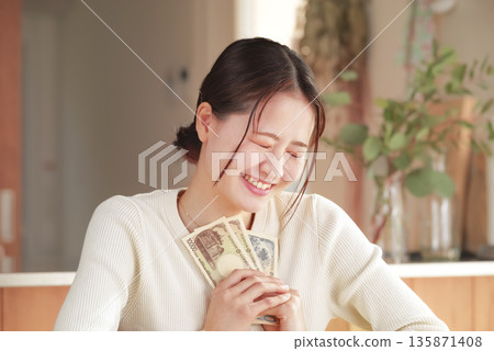 A woman who looks happy with money in her hands A woman who looks happy with money in her hands 135871408