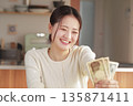 A woman who looks happy with money in her hands 135871411