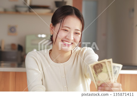一個手裡拿著錢,看起來很開心的女人 一個手裡拿著錢,看起來很開心的女人 135871411