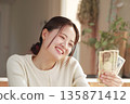 A woman who looks happy with money in her hands 135871412