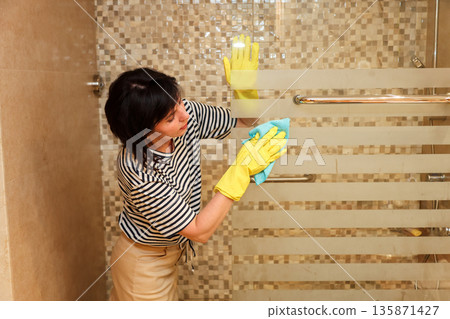 A housewife washes glass in a shower stall A housewife washes glass in a shower stall 135871427