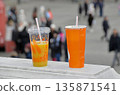 Drink in paper and plastic cups with straws. Bright orange color. 135871541