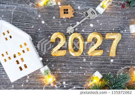 New Year 2027 golden numbers and House key with tiny form of home on festive grey wooden background flatlay, lights of garlands, greeting card. Housing, real estate, relocation, mortgage, insurance New Year 2027 golden numbers and House key with tiny form of home on festive grey wooden background flatlay, lights of garlands, greeting card. Housing, real estate, relocation, mortgage, insurance 135872062