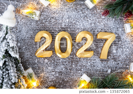 Happy New Year golden numbers 2027 on cozy festive grey wooden background with Christmas tree, snow, lights of garlands. Greetings, postcard. Calendar, cover 135872065