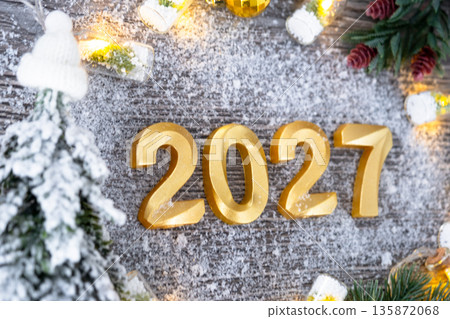 Happy New Year golden numbers 2027 on cozy festive grey wooden background with Christmas tree, snow, lights of garlands. Greetings, postcard. Calendar, cover 135872068