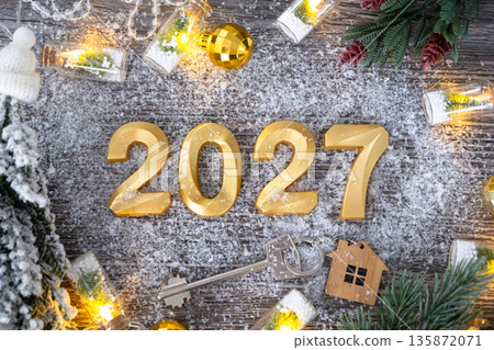 New Year 2027 golden numbers and House key with tiny form of home on festive grey wooden background flatlay, lights of garlands, greeting card. Housing, real estate, relocation, mortgage, insurance New Year 2027 golden numbers and House key with tiny form of home on festive grey wooden background flatlay, lights of garlands, greeting card. Housing, real estate, relocation, mortgage, insurance 135872071