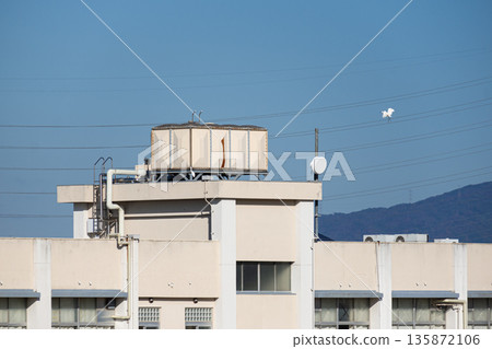 A rooftop water tank at Tenbi Nishi Elementary School in Matsubara City, Osaka Prefecture, and a white egret flying in the blue sky (anime style, copy space) A rooftop water tank at Tenbi Nishi Elementary School in Matsubara City, Osaka Prefecture, and a white egret flying in the blue sky (anime style, copy space) 135872106