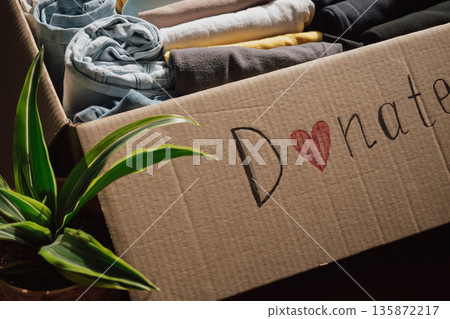 Box filled with neatly folded clothes ready for donation at a local charity for those in need Box filled with neatly folded clothes ready for donation at a local charity for those in need 135872217