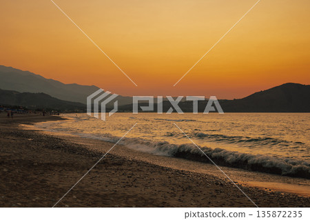 Vibrant orange and pink colors of the sun setting over the tranquil sea Vibrant orange and pink colors of the sun setting over the tranquil sea 135872235