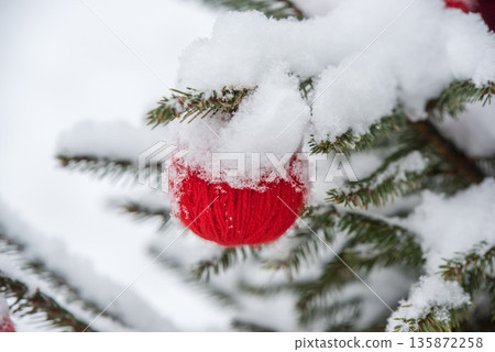 Red wool ball hanging on the green branches of a Christmas tree. Red wool ball hanging on the green branches of a Christmas tree. 135872258